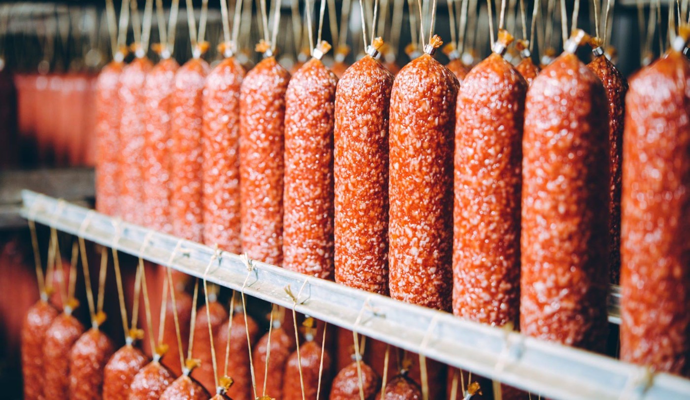 Rows of cured sausages hanging in a processing facility