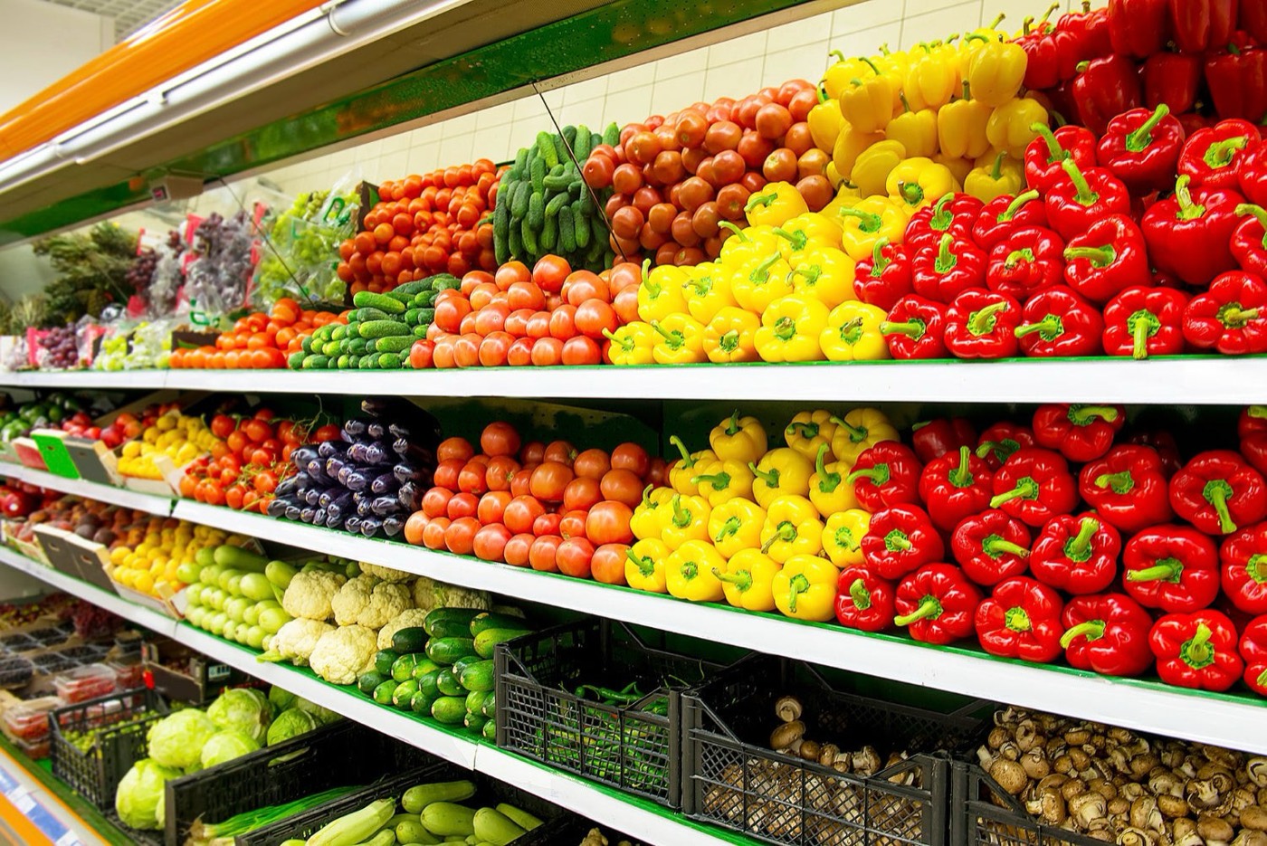 Supermarket shelves stocked with fresh peppers, tomatoes and vegetables