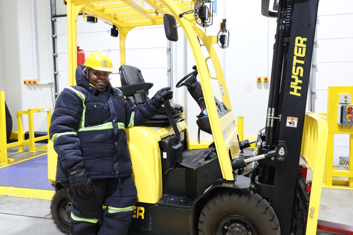 Cold Solutions team member in cold-room gear beside a forklift